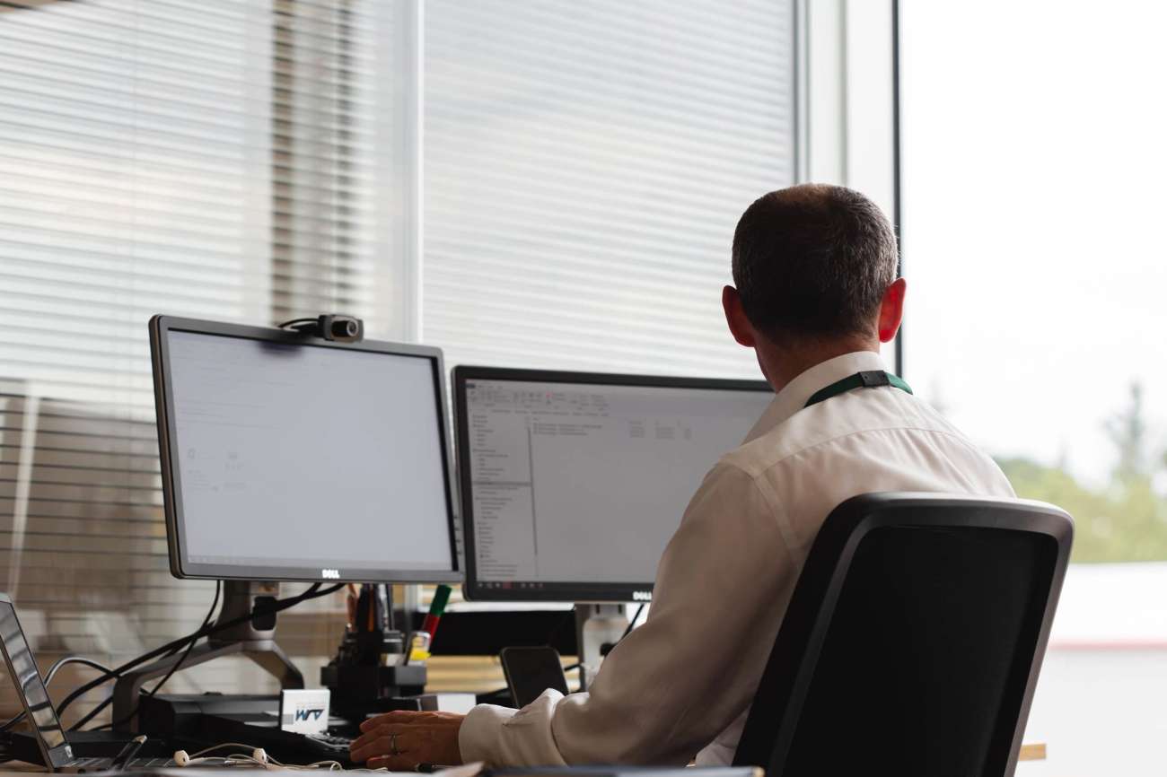 Person from behind sitting on computer with two screens